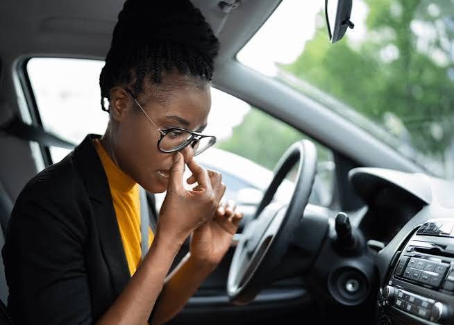 Driver holding her nose because of a bad smell inside the car