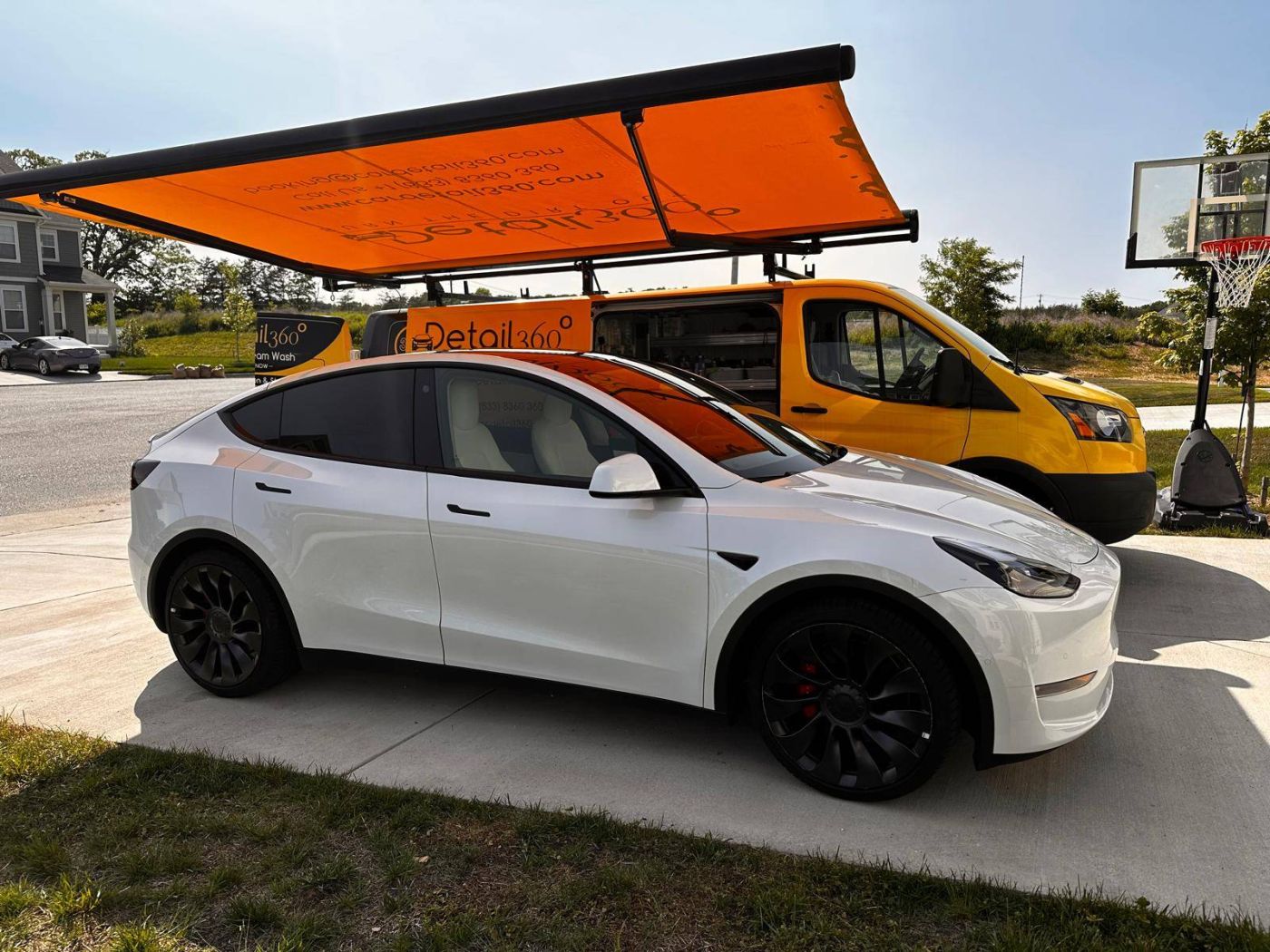 Car Detail 360 mobile van servicing a Tesla Model Y in a customer's driveway